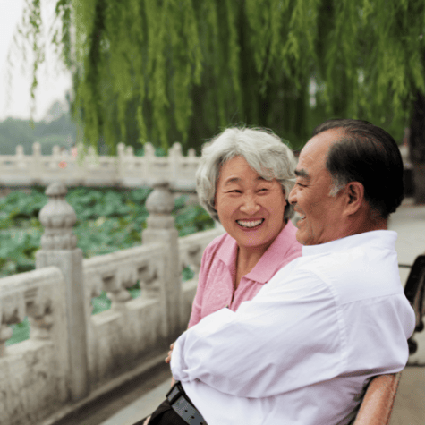 older Asian couple sitting on a bench